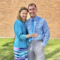 a man and woman standing in front of a brick building