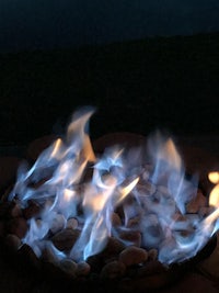 a fire pit with blue flames sitting on top of rocks