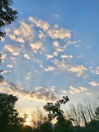 a sunset with clouds and trees in the background