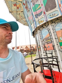 a man sitting on a carousel in a park