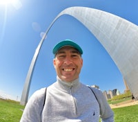 a man smiling in front of the gateway arch in st louis