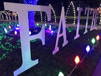 a sign that says faith is lit up with christmas lights