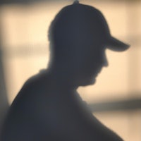 a silhouette of a man wearing a baseball cap