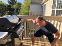 a man standing on a deck with a bbq grill