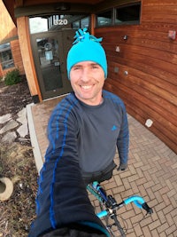 a man wearing a blue beanie and riding a bike in front of a building