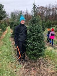 a man in a blue hat is standing next to a christmas tree