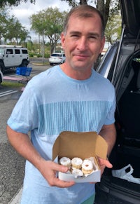 a man holding a box of donuts