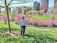 a man standing in a park with trees in bloom