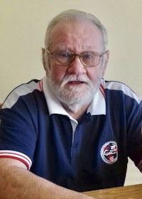 an older man with a beard and glasses sitting at a table