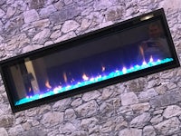 a man is standing in front of a fireplace with blue flames