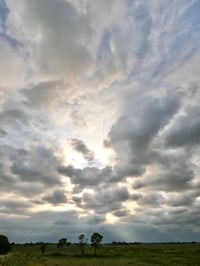 a cloudy sky over a grassy field