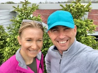 a man and woman taking a selfie in front of bushes