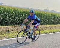 a man riding a bike on a road near a corn field