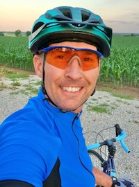 a man on a bike smiling in front of a corn field